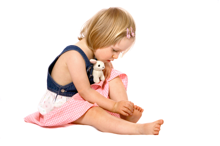 A little girl sitting on the floor with a teddy bear.